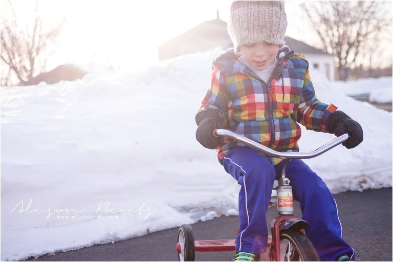 boy on trike by snowbank